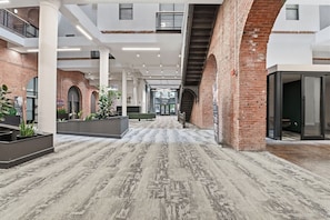 Un espacio interior amplio con techo alto, paredes de ladrillo y alfombra estampada.