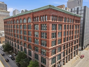 A multi-story building with a red brick facade, large windows, and a flat roof.