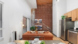 A modern kitchen with a brick wall, stainless steel appliances, and a dining area with a table set for two.