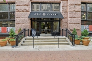 A building entrance with a black awning labeled 'SIX CORD,' steps leading up to the door, and potted plants on either side. - Modern 2BR/2BA Loft | Resort Amenities + Downtown St. Louis (St. Louis)
