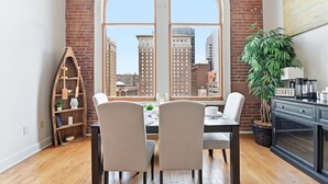 Un espace repas doté d’une grande fenêtre en arc de cercle, d’un coin café et d’une plante.