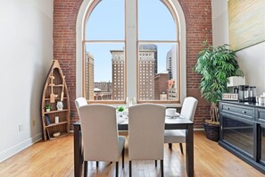 Un espace repas doté d’une grande fenêtre en arc de cercle, d’un coin café et d’une plante.