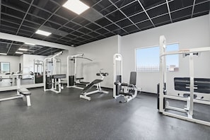 Un gimnasio con diverso equipo de ejercicio, una banca y un ventanal con vistas.