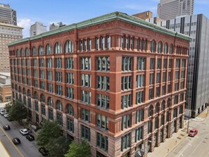 A multi-story building with a red brick facade, large windows, and a flat roof. - 1BR Loft | Downtown STL + Rooftop, Sauna, Firepit (St. Louis)