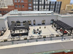 Una terraza en la azotea con mobiliario exterior, un hogar central y vistas de los edificios circundantes.