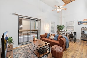 A living room with a sofa, coffee table, ottoman, and a dining area with a table and chairs.