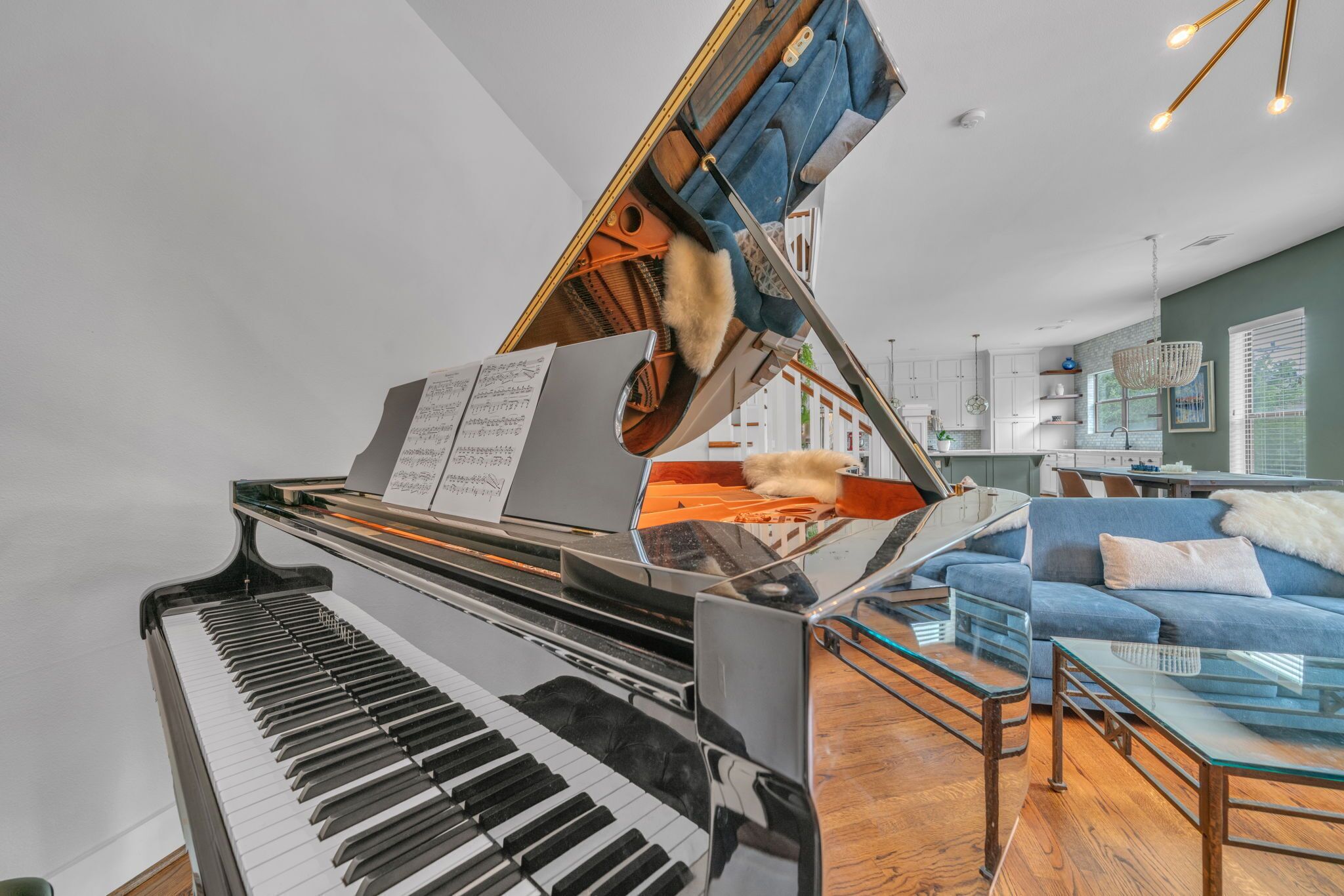 A grand piano in a living room with a sofa and a glass coffee table.