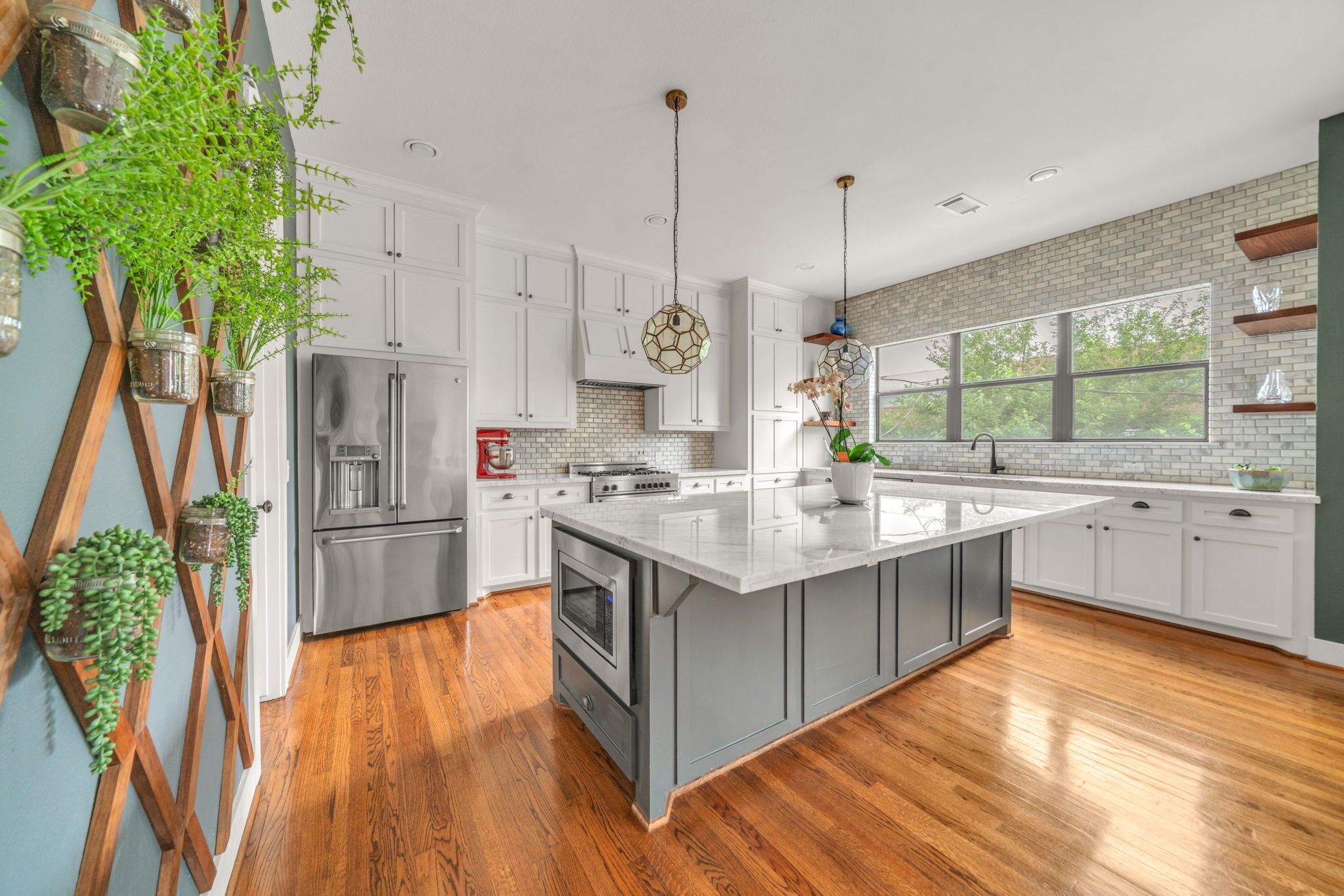 A modern kitchen with white cabinets, a large island, and wooden flooring.