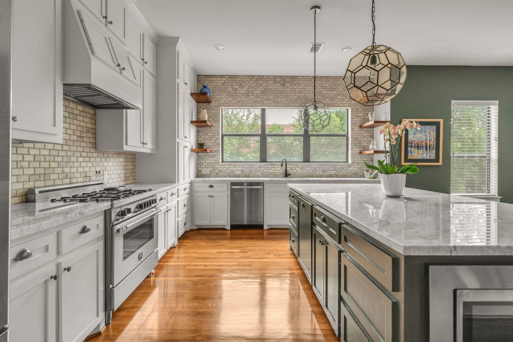 A modern kitchen with white cabinetry, a large island, a brick backsplash, and a hanging pendant light.