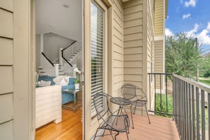 A balcony with a wooden floor, a white couch, a small table, and two chairs. - THE PARKER, A Modern Retreat Near Everything: 3 BR, 3.5 bathroom house Sleeps 8 (Houston)