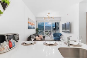 A modern kitchen with a dining area, a view of a cityscape, and a blue chair. - 11th Floor Luxury Apartment W/ AC (San José)