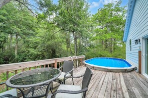 A wooden deck with a glass table and chairs, a small pool, and a house with a blue exterior. - 🦩Book Me Baby! Juan Sweet Beach House in Santa Rosa Beach🦩 (Santa Rosa Beach)