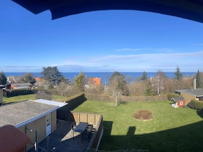 Ein Wohngrundstück mit Terrasse, Rasen und Blick auf das Meer.