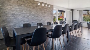 A modern dining area with a brick wall, a long table, and black chairs. - 5 Star Holiday Home in Allinge (Allinge)