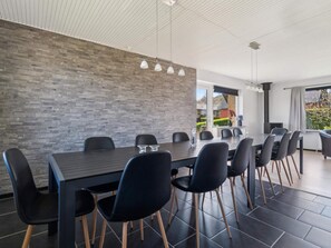 Ein moderner Essbereich mit Backsteinwand, einem langen Tisch und schwarzen Stühlen.