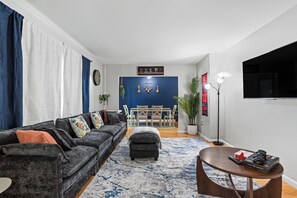 A living room with a sofa, ottoman, coffee table, and a dining area with chairs and a table.