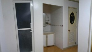 Een hal met een deur, een kleine kitchenette en een deur met een rond raam.