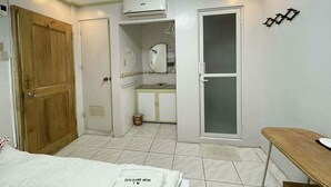 Een slaapkamer met een bed, een houten deur, een badkamer met een spiegel en een raam.