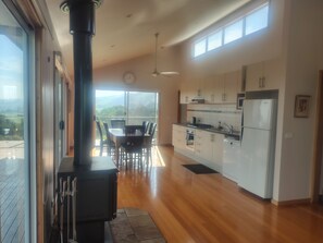 A modern kitchen with a large island, a dining area with chairs, and a view through large windows.