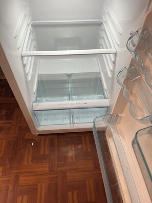 Ein offener Kühlschrank mit zwei Ablagen und einem Gefrierfach.