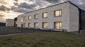 Een modern gebouw met een plat dak, grote ramen en een verharde oprit.