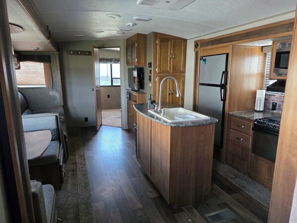 Una cocina compacta para autocaravana con armarios de madera, un lavamanos, una estufa y un refrigerador.