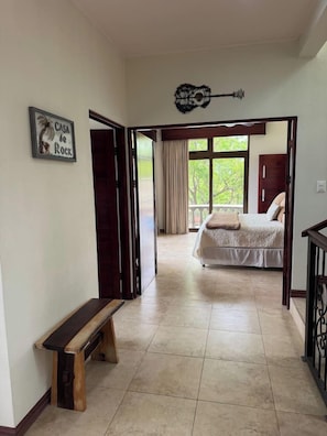 Ein Schlafzimmer mit einem Bett, einer Bank und einer Tür, die auf einen Balkon führt.