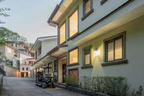 Un edificio residencial de varios pisos con un camino cubierto y un vehículo estacionado.