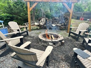 Ein Lagerfeuer, umringt von Adirondack-Stühlen, im Freien.