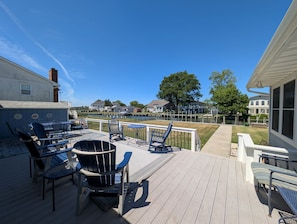 Eine Terrasse mit Gartenmöbeln, Blick auf ein Gewässer und Häuser im Hintergrund.
