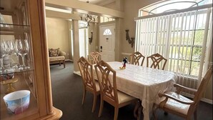 Un comedor con una mesa, sillas y un aparador de vidrio con copas de vino.