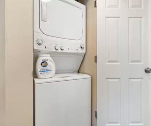 Un área de lavandería con lavadora y una botella de detergente All.