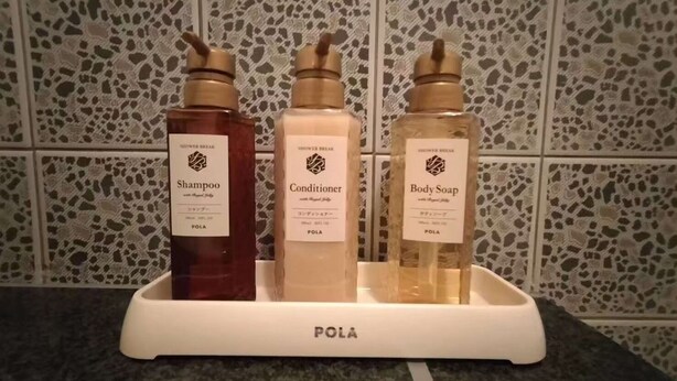 Un baño con estación de ducha que ofrece botellas de champú, acondicionador y jabón corporal.