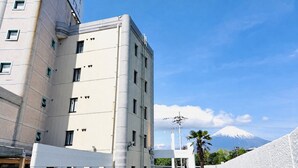 Edifício de hotel com uma placa visível, várias janelas e vista para uma montanha.