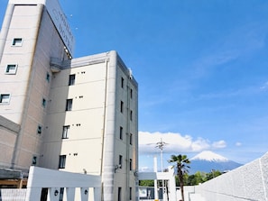 Un edificio de hotel con un letrero llamativo, varias ventanas y vistas a una montaña.