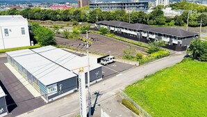 Un hotel con estacionamiento, un edificio de techo plano y una montaña al fondo.