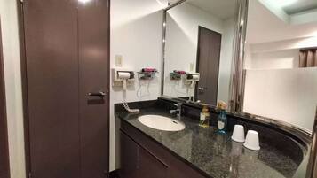 Un baño de hotel con una puerta de madera oscura, un lavamanos blanco, un espejo grande y un perchero para toallas.