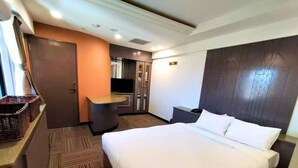 Quarto de hotel com cama, escrivaninha, televisão e guarda-roupa.