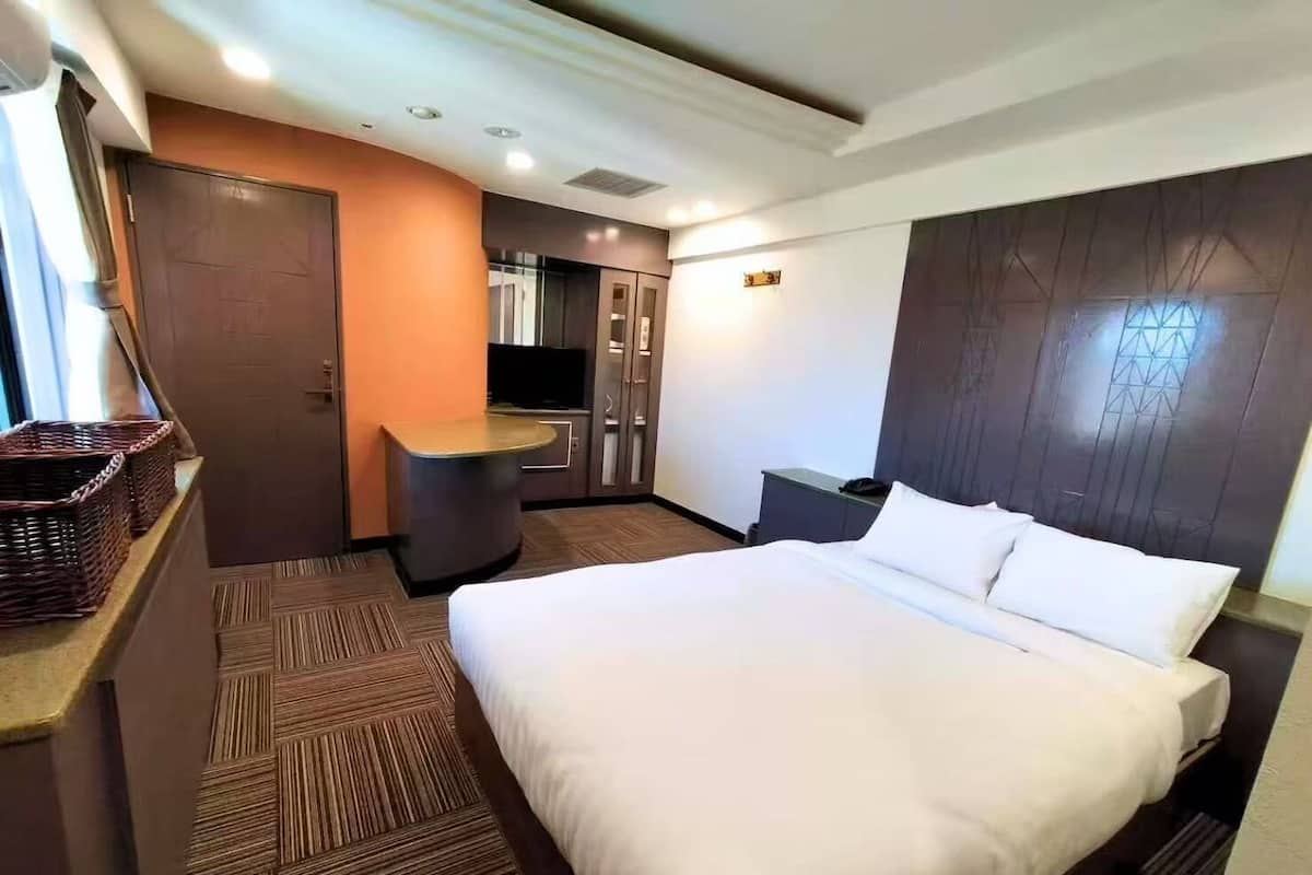 Una habitación de hotel con una cama, un escritorio, un televisor y un armario.