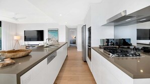 Una cocina moderna con una isla central, electrodomésticos de acero inoxidable y vistas al área de estar.
