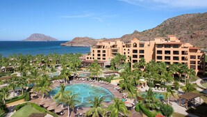 Een resort met meerdere gebouwen, een groot centraal zwembad en palmbomen.