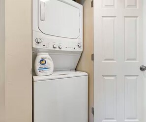 Un área de lavandería con lavadora y una botella de detergente All.