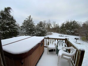 A wooden deck with a hot tub, two white plastic chairs, and a bench. - Dreams End Deerrun Cabin (Connersville)