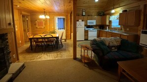 Interior d'una cabana de fusta amb menjador, cuina i sala d'estar.