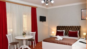Ein Hotelzimmer mit einem Bett, einem runden Esstisch mit Stühlen, einem Fernseher und einem roten Teppichboden.