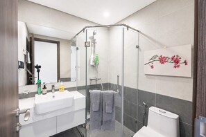 Ein modernes Badezimmer mit Duschkabine aus Glas, einem weißen Waschbecken und einer Toilette.