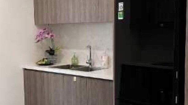 Une cuisine moderne avec des meubles gris, un réfrigérateur noir et un sol en marbre.