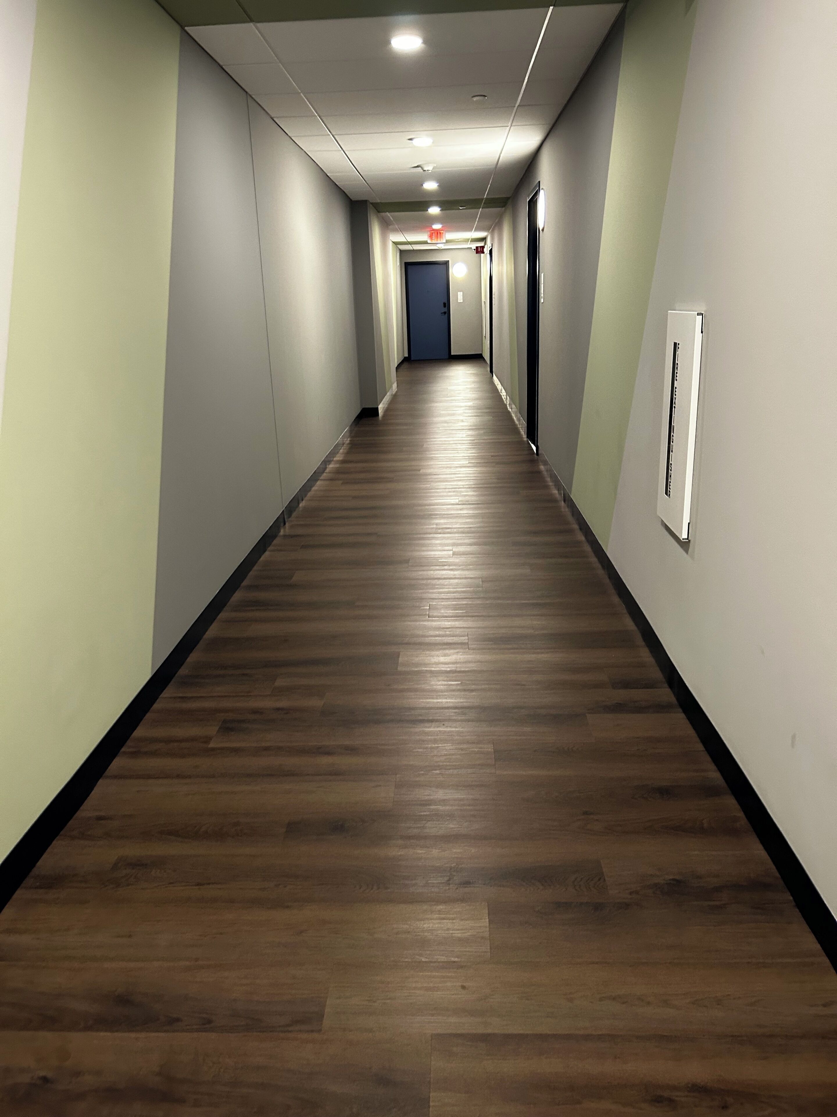 A long, narrow hallway with wooden flooring and light-colored walls.