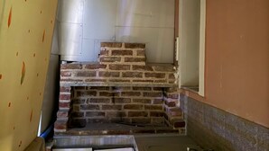 Una cocina con pared de ladrillo, un lavamanos y una ventana.