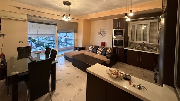 Una sala de estar moderna con sofá, mesa de comedor y sillas, una cocina equipada y un ventanal con vistas.
